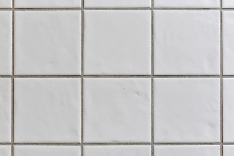 White ceramic tiles arranged in a grid pattern on a wall surface