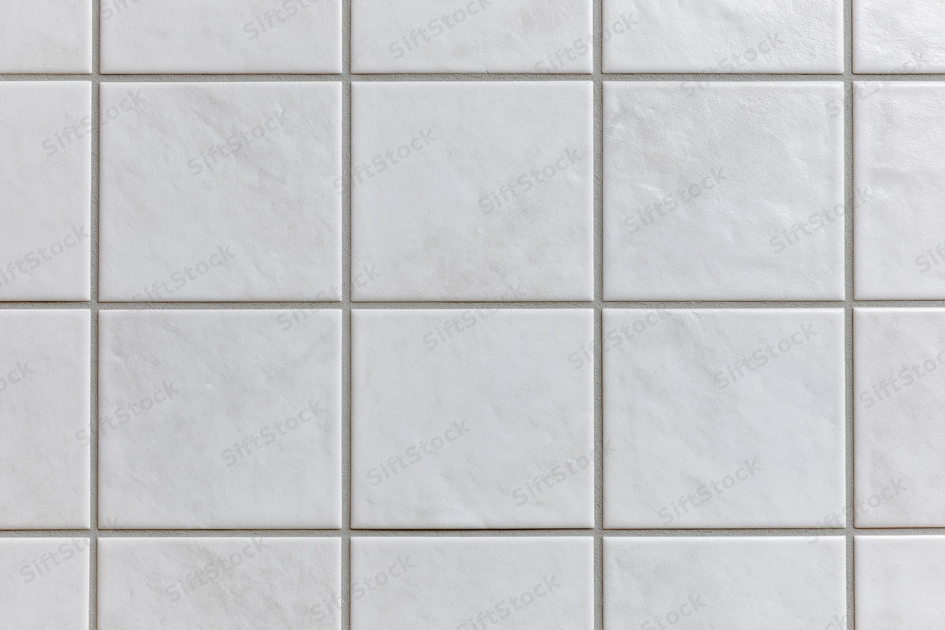 White ceramic tiles arranged in a grid pattern covering a wall surface