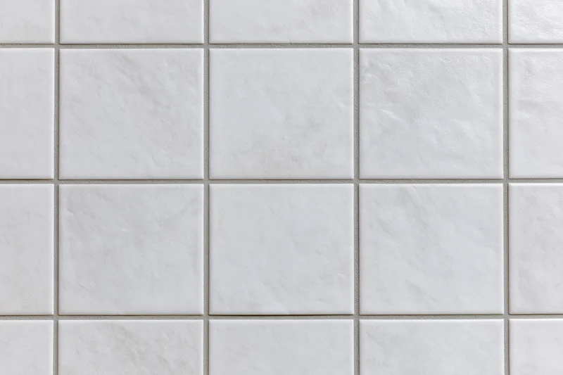 White ceramic tiles arranged in a grid pattern covering a wall surface