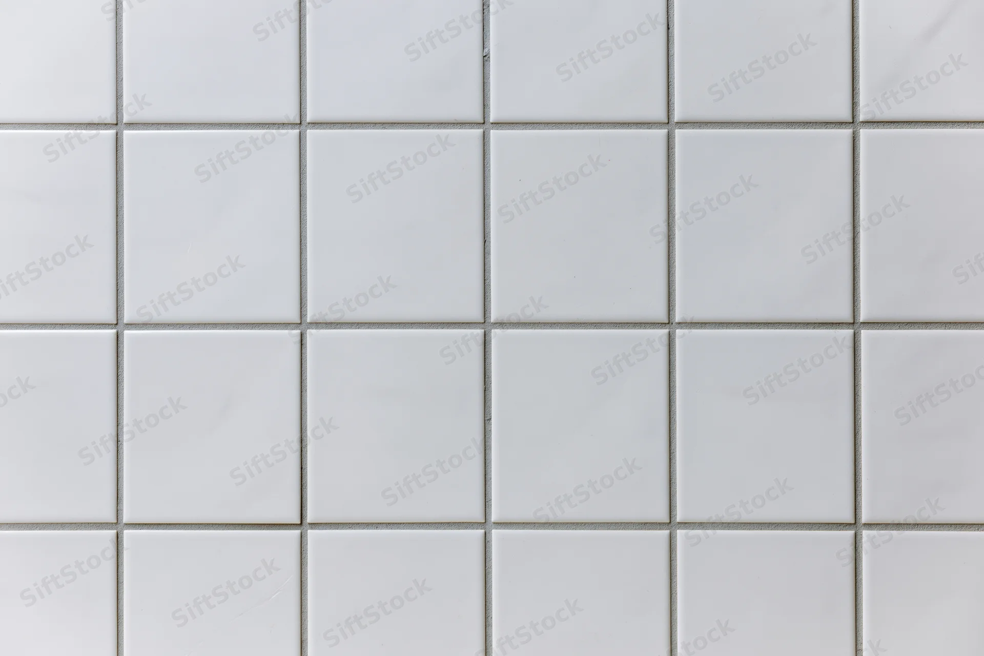 White ceramic tiles arranged in a grid pattern covering a wall surface