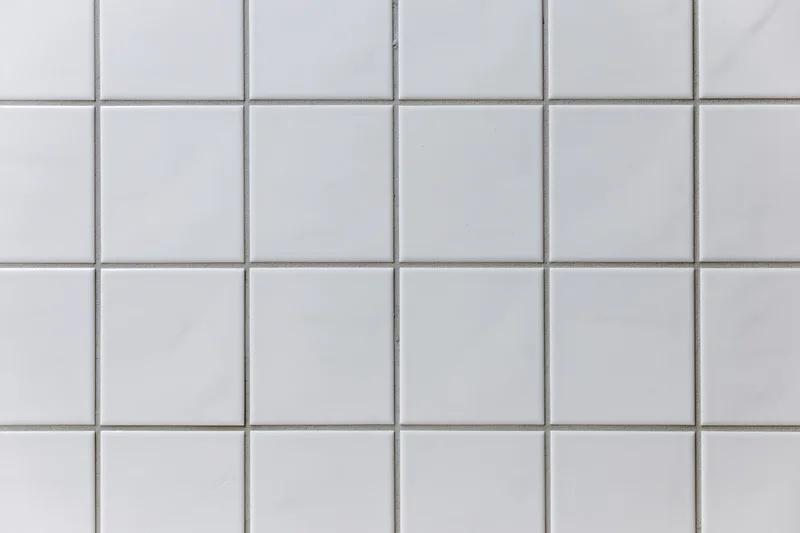White ceramic tiles arranged in a grid pattern covering a wall surface