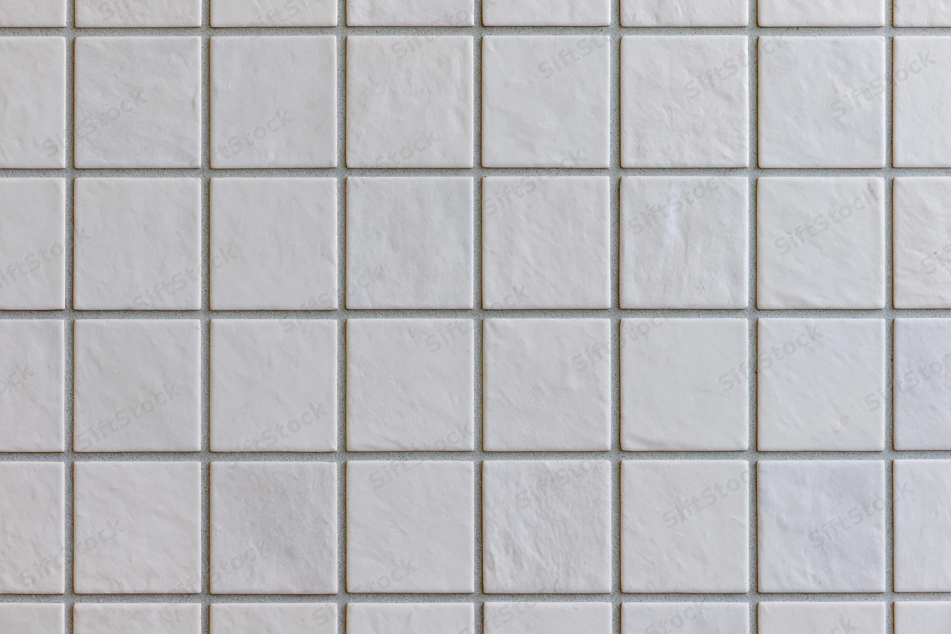 White ceramic tiles arranged in a grid pattern covering a wall surface