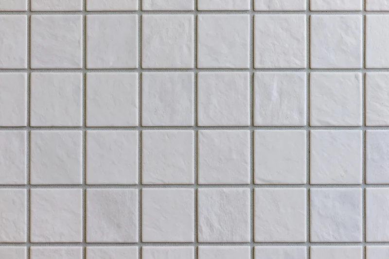 White ceramic tiles arranged in a grid pattern covering a wall surface