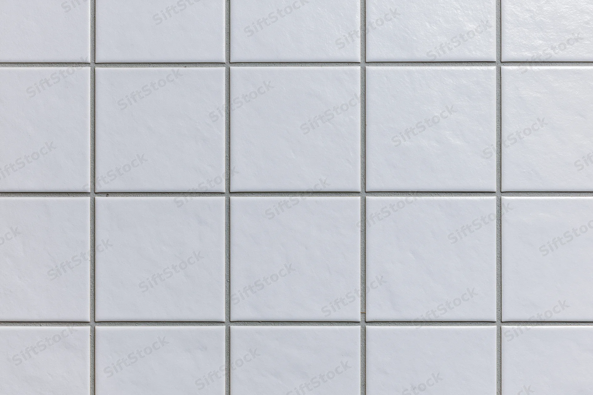 White ceramic tiles arranged in a grid pattern covering a wall surface