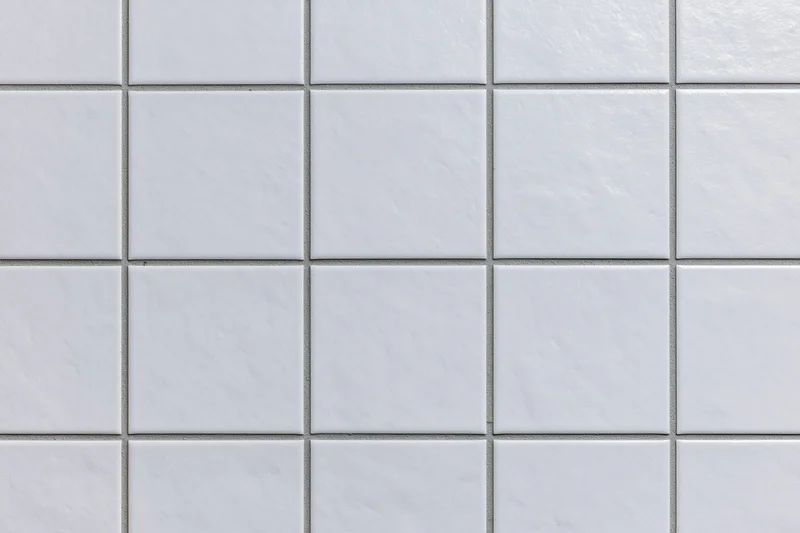 White ceramic tiles arranged in a grid pattern covering a wall surface