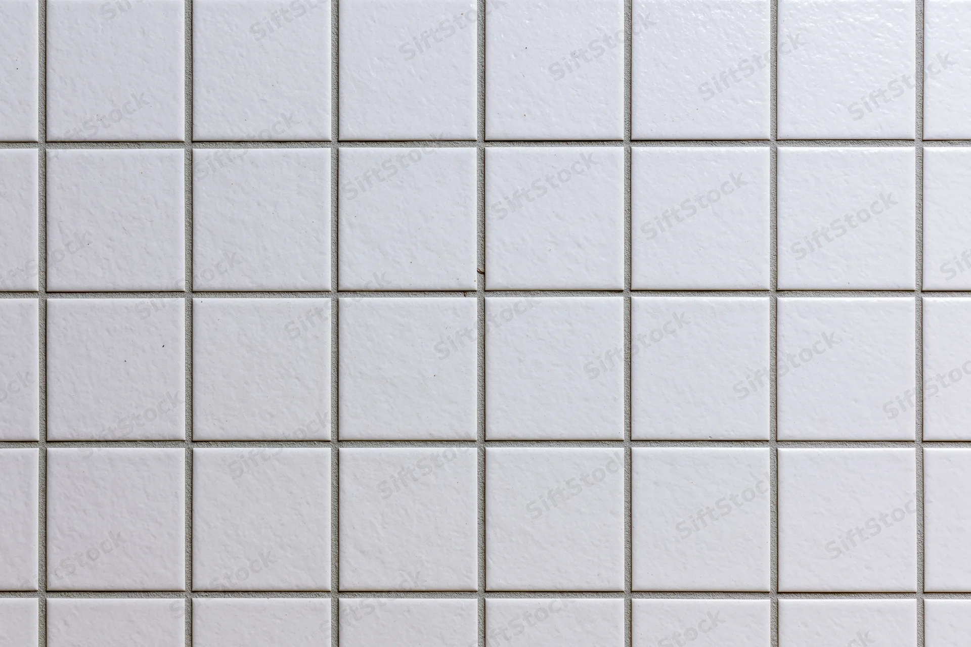 White ceramic tiles arranged in a grid pattern covering a wall surface