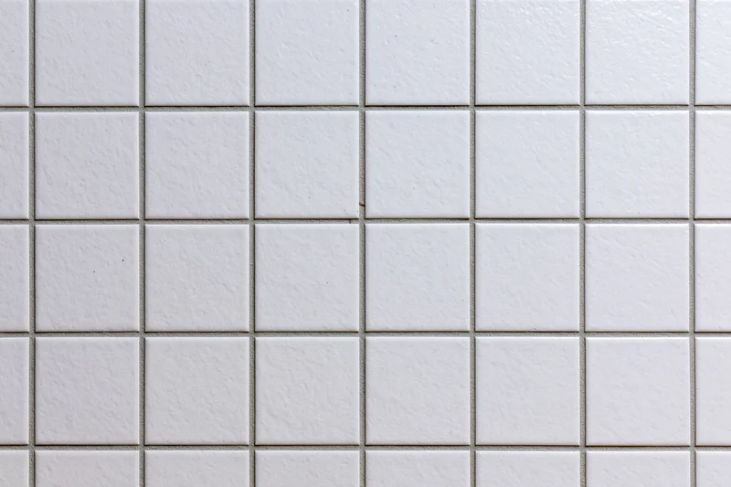 White ceramic tiles arranged in a grid pattern covering a wall surface