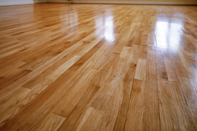 Polished hardwood floor stretching into the distance with reflective surface and visible wood grain