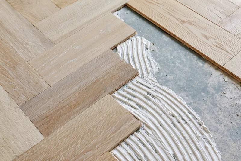 Hardwood parquet flooring being installed with adhesive on a concrete subfloor