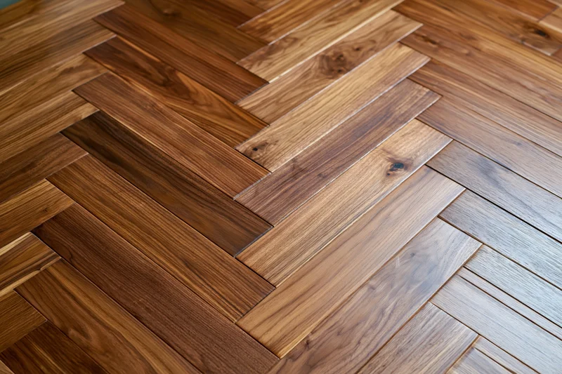 Herringbone parquet wood floor filling the frame with natural grain variation and warm tones