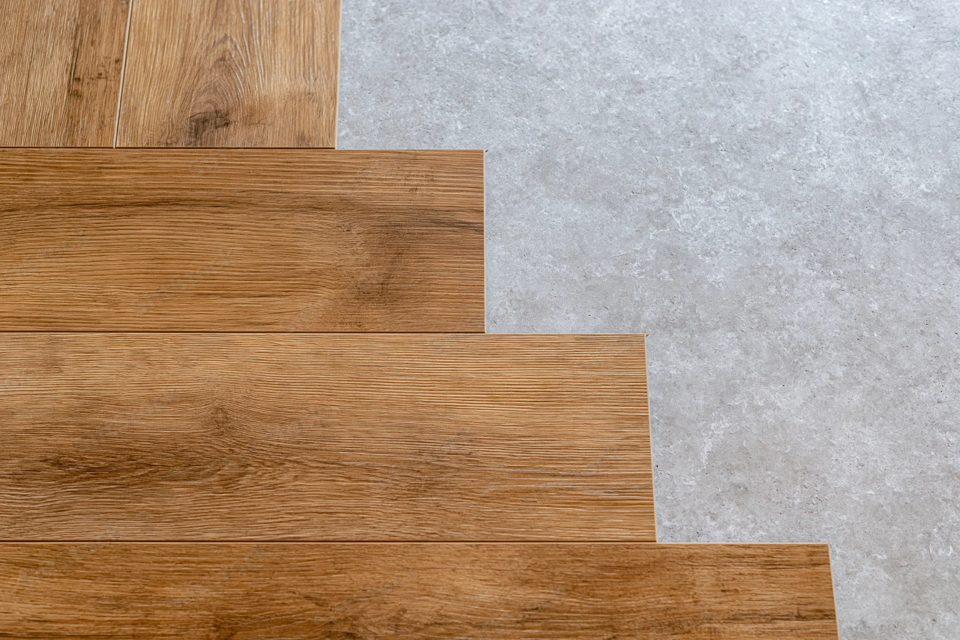 Laminate wood flooring planks laid in progress on concrete subfloor showing edge transition