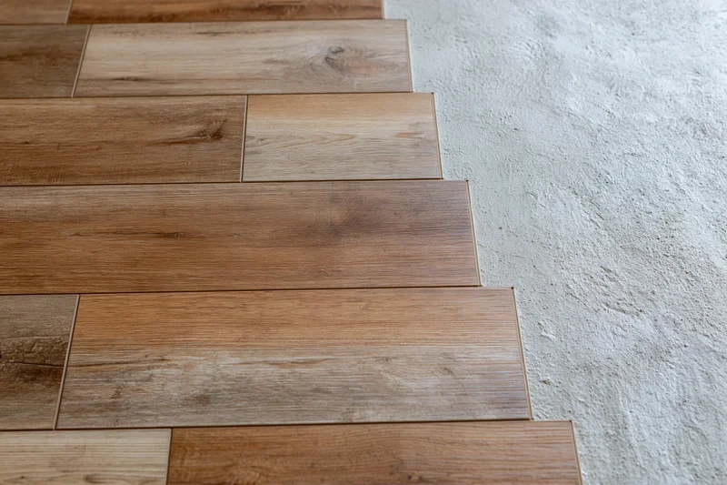Laminate wood flooring planks laid in staggered pattern on concrete subfloor during installation