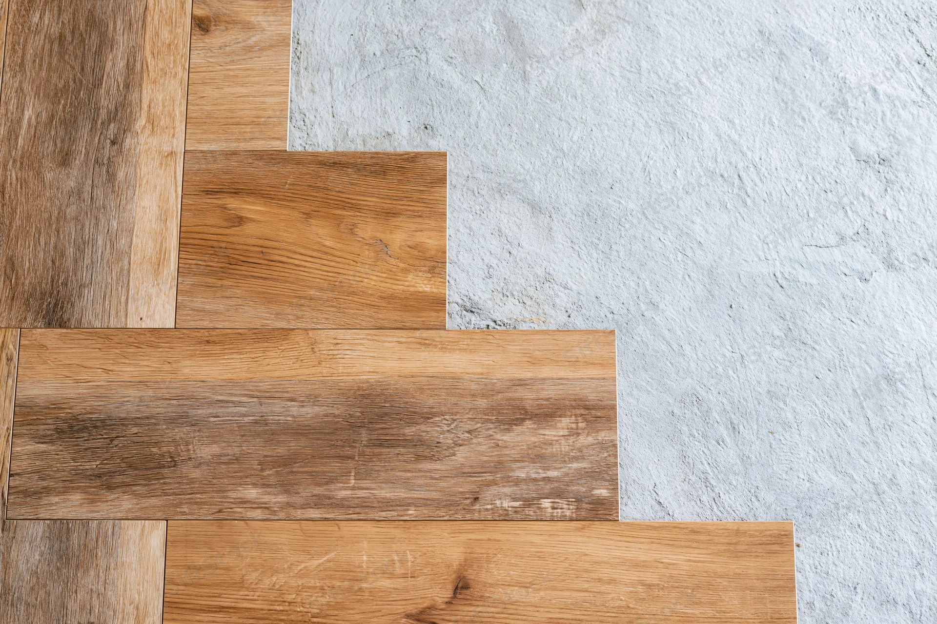 Laminate wood flooring planks laid in staggered pattern on concrete subfloor during installation