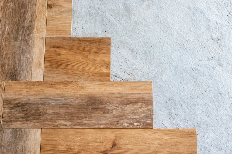 Laminate wood flooring planks laid in staggered pattern on concrete subfloor during installation