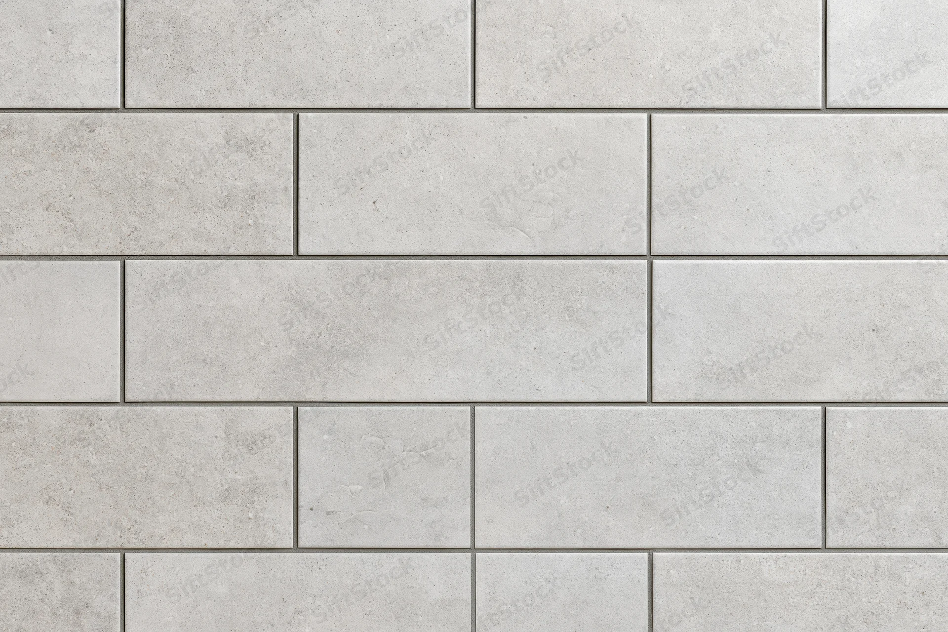 Large-format concrete-look ceramic tiles arranged in a staggered pattern on a wall