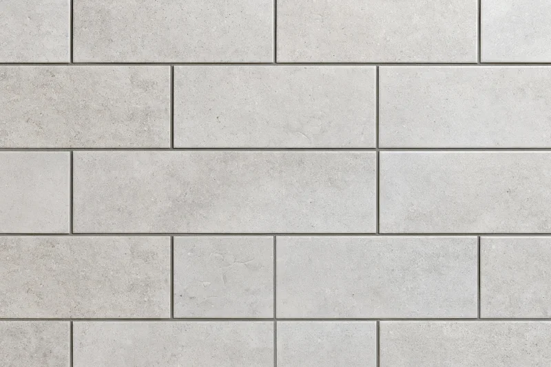Large-format concrete-look ceramic tiles arranged in a staggered pattern on a wall