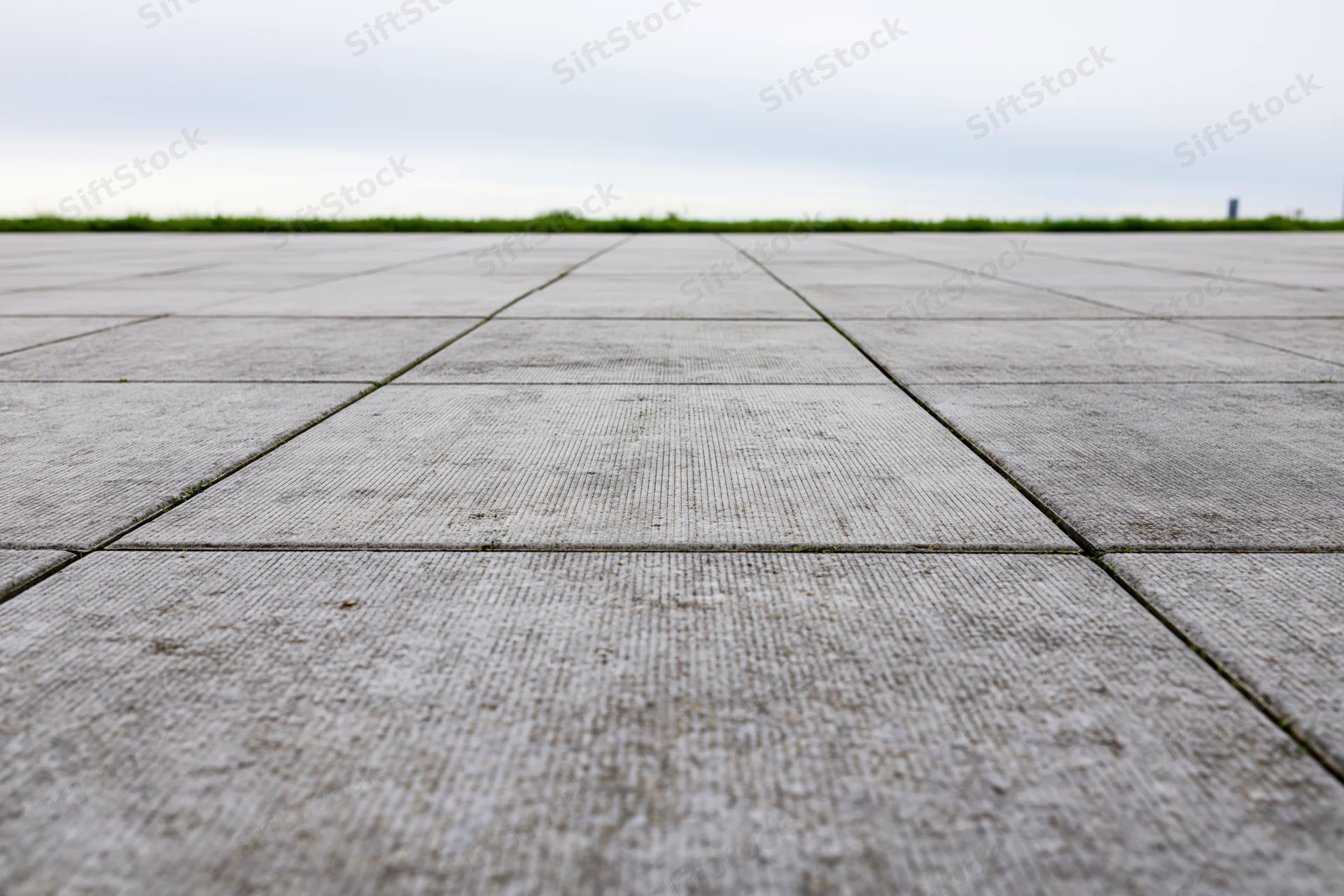 Concrete tiled plaza floor receding into the distance under an overcast sky