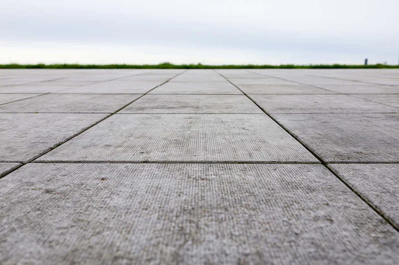 Concrete tiled plaza floor receding into the distance under an overcast sky