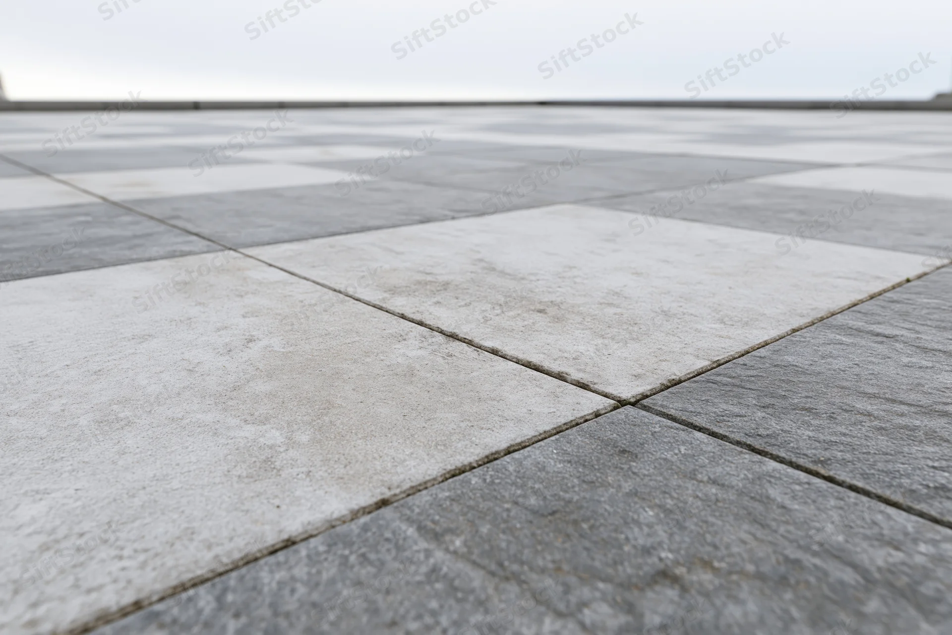 Square concrete paving tiles arranged in a checkered pattern on an outdoor ground surface
