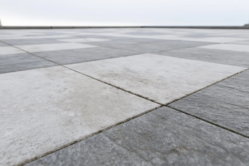 Square concrete paving tiles arranged in a checkered pattern on an outdoor ground surface