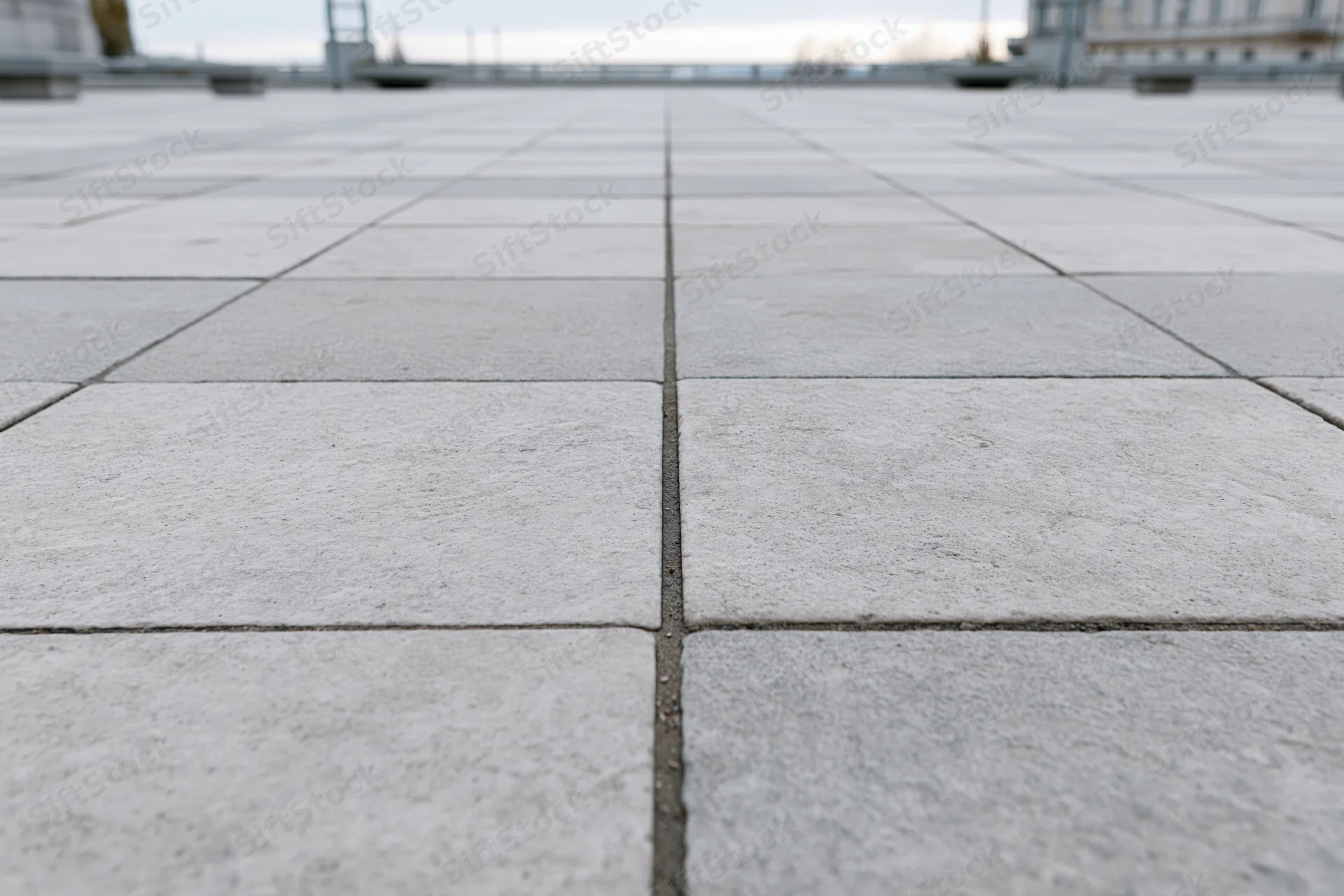 Square concrete paving tiles arranged in a grid pattern on an urban plaza floor