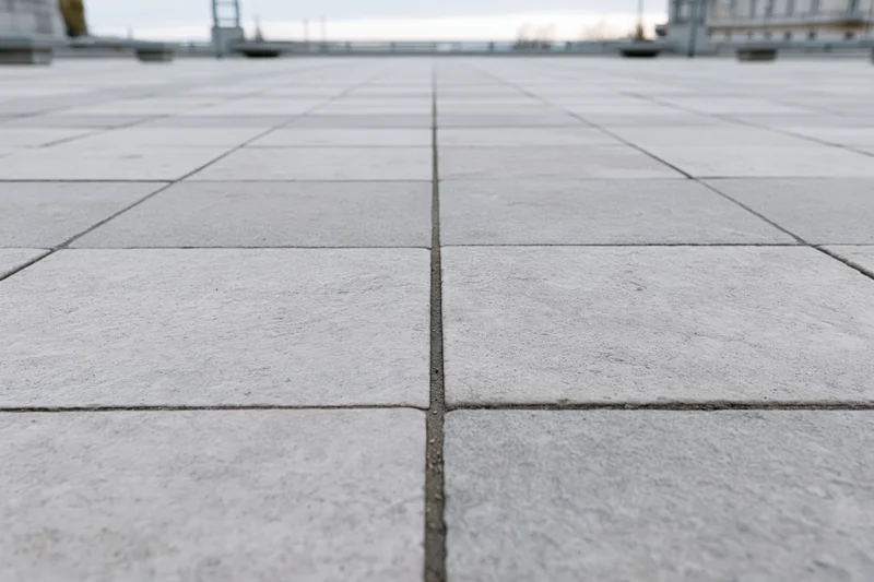 Square concrete paving tiles arranged in a grid pattern on an urban plaza floor
