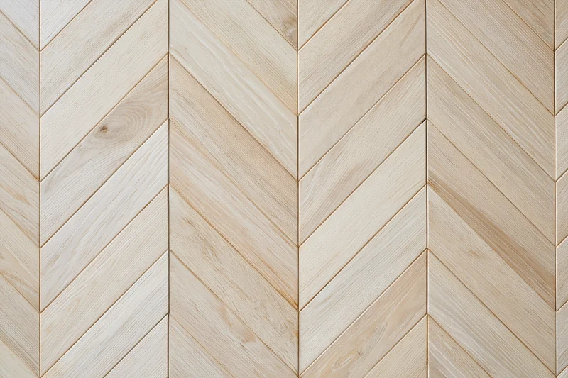 Light oak parquet flooring arranged in a chevron pattern for interior use