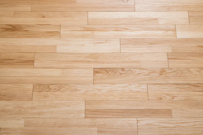 Light oak hardwood parquet floor filling the frame with natural wood grain texture