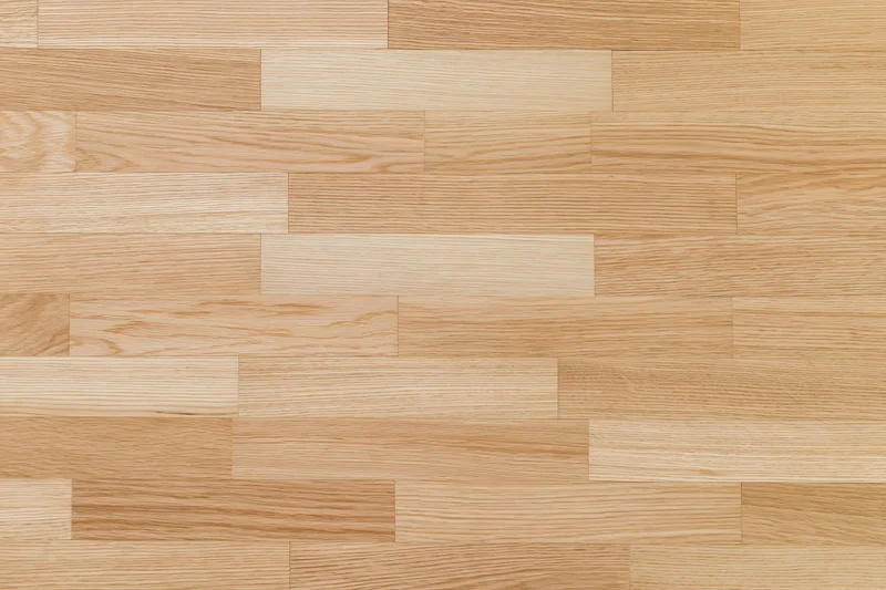 Light oak hardwood parquet floor filling the frame with natural wood grain pattern