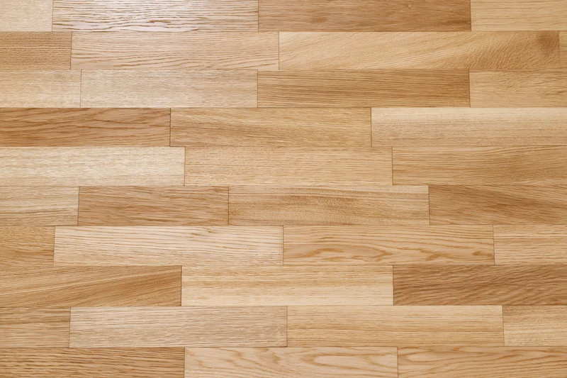 Light oak hardwood parquet floor filling the frame with natural wood grain pattern