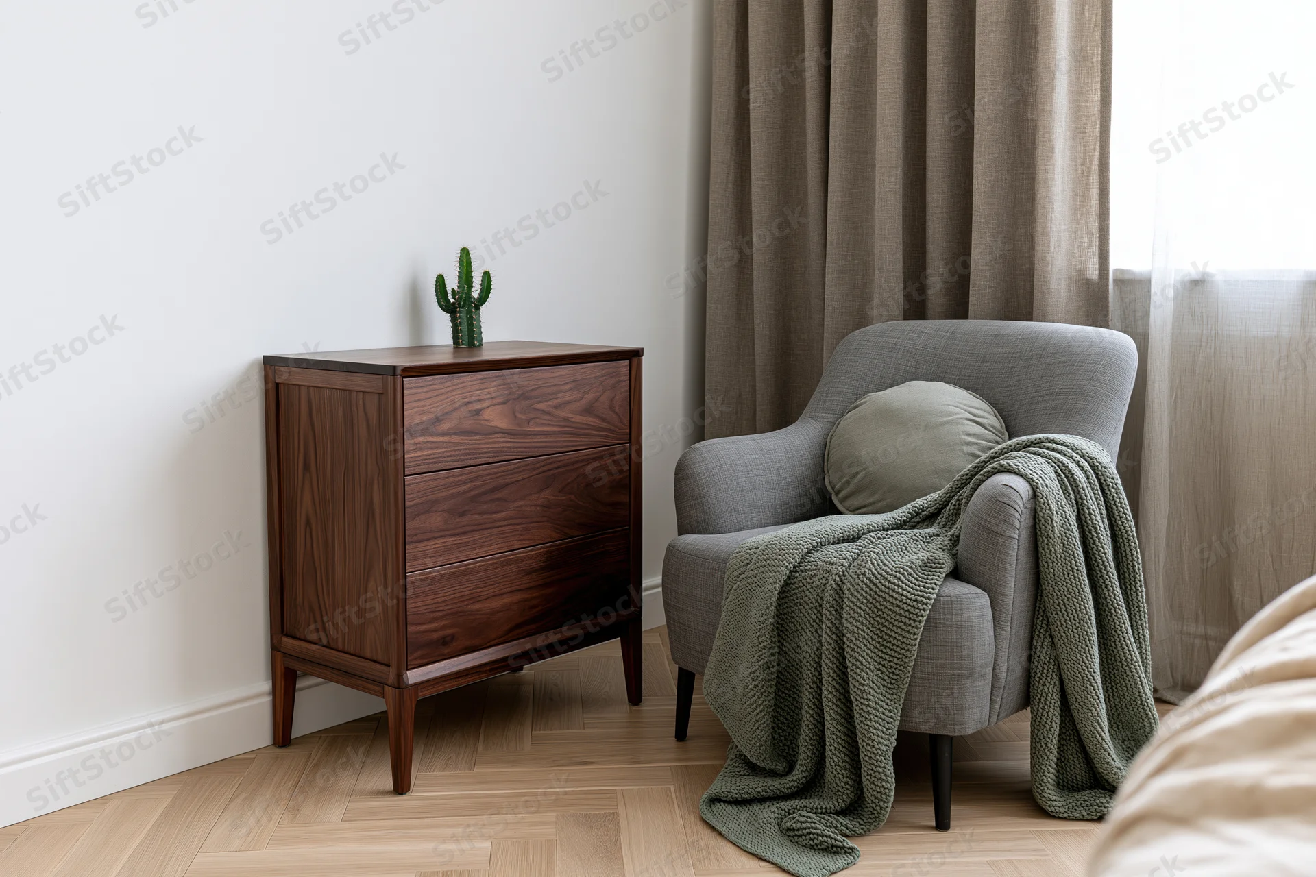 Dark walnut dresser with three drawers beside a gray armchair draped with a green knit blanket in a bedroom corner near a window with beige curtains
