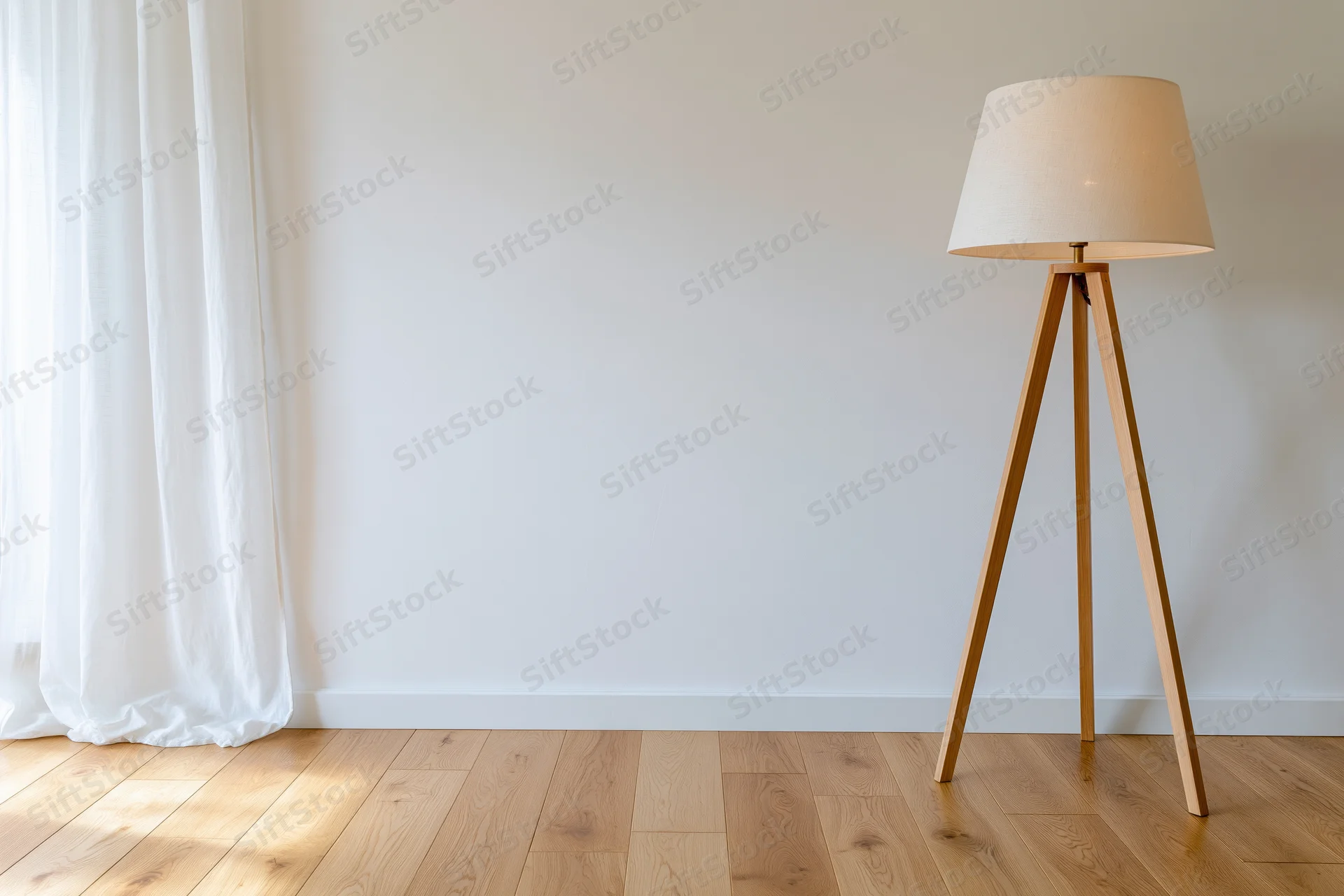 Wooden tripod floor lamp standing in minimalist empty room interior near white curtain and window