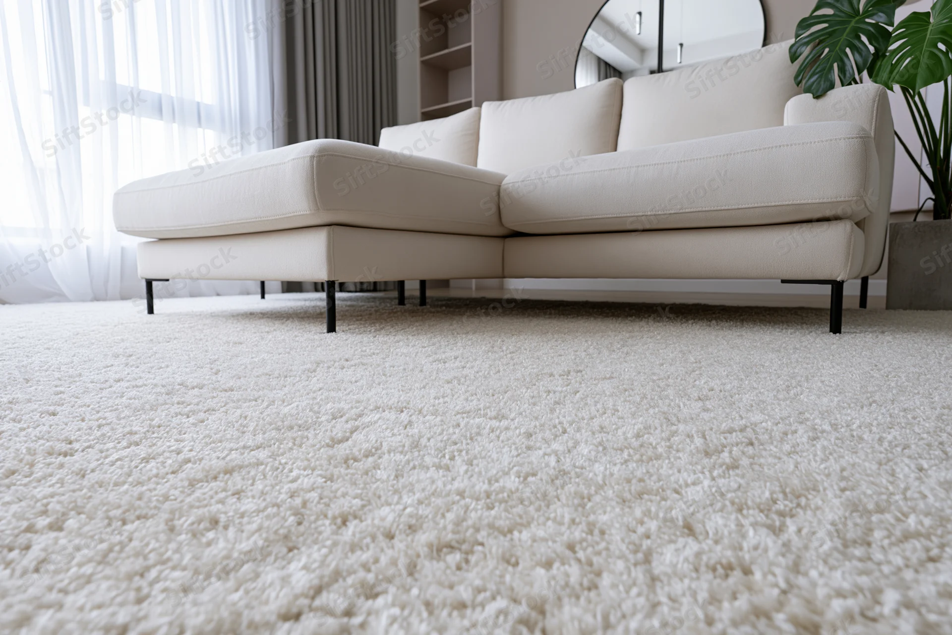 White sectional sofa on beige carpet in minimalist living room interior