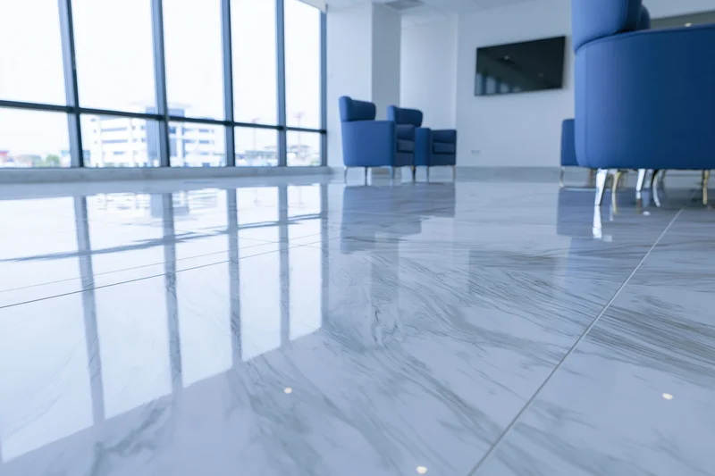 Modern office lobby with glossy epoxy resin floor and blue chairs near large windows