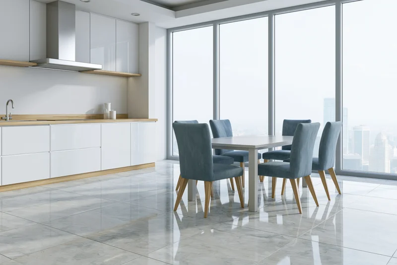Modern open-plan kitchen and dining area with white cabinetry, wooden countertops, marble flooring, and city view through large windows