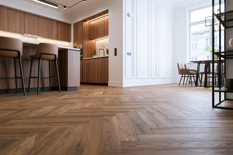 Modern open-plan kitchen and dining area with wood herringbone flooring and white paneling
