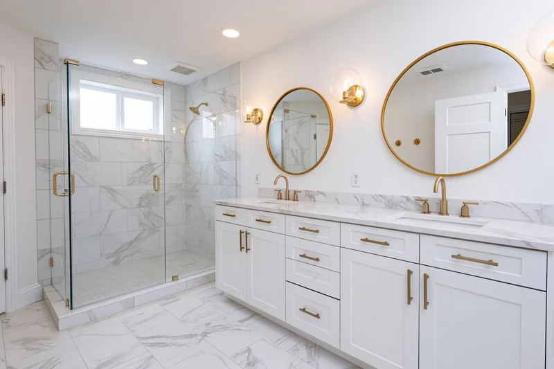 Modern primary bathroom with double vanity and round mirrors above marble countertop