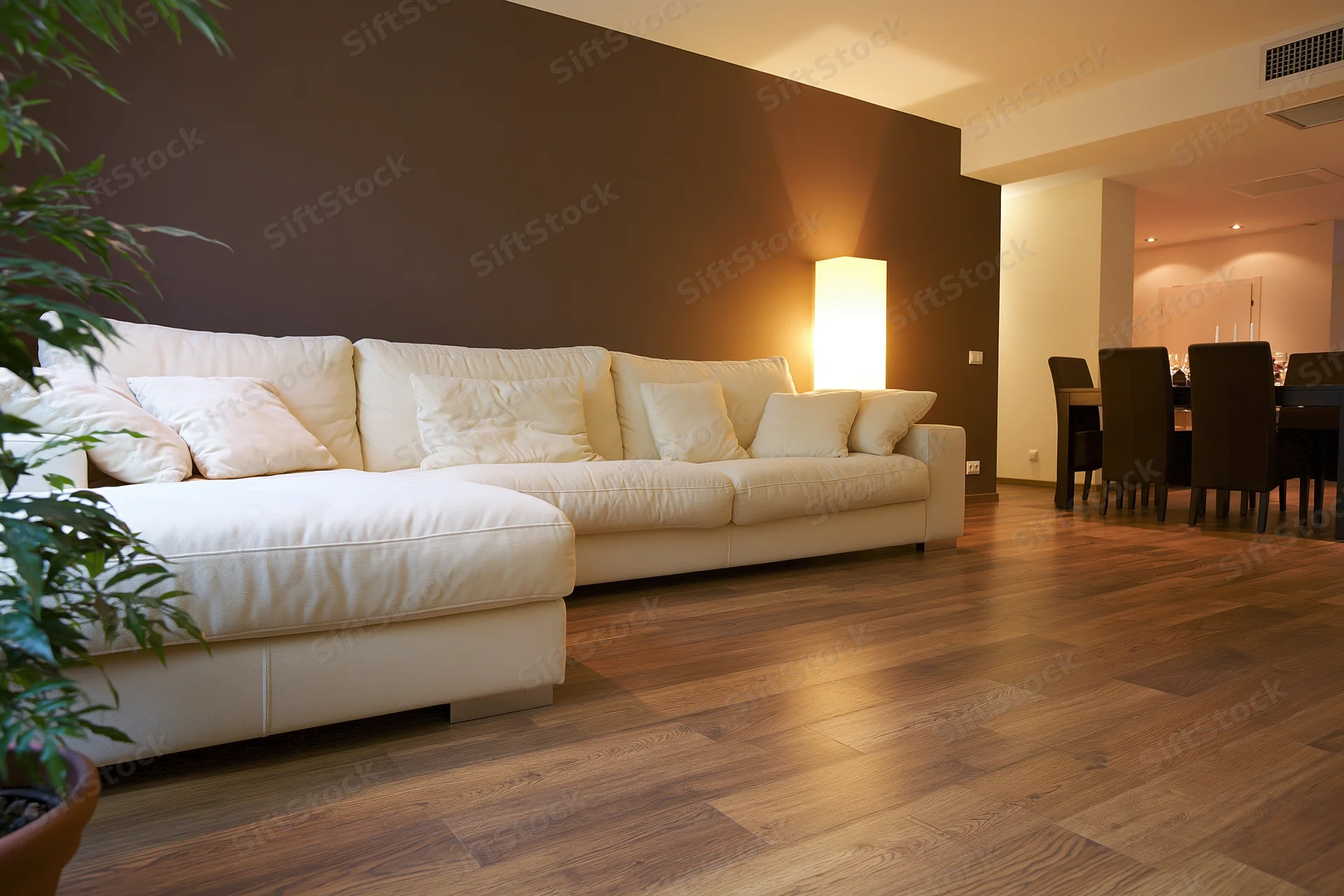 White sectional sofa in open-plan living and dining room with warm lighting and hardwood flooring