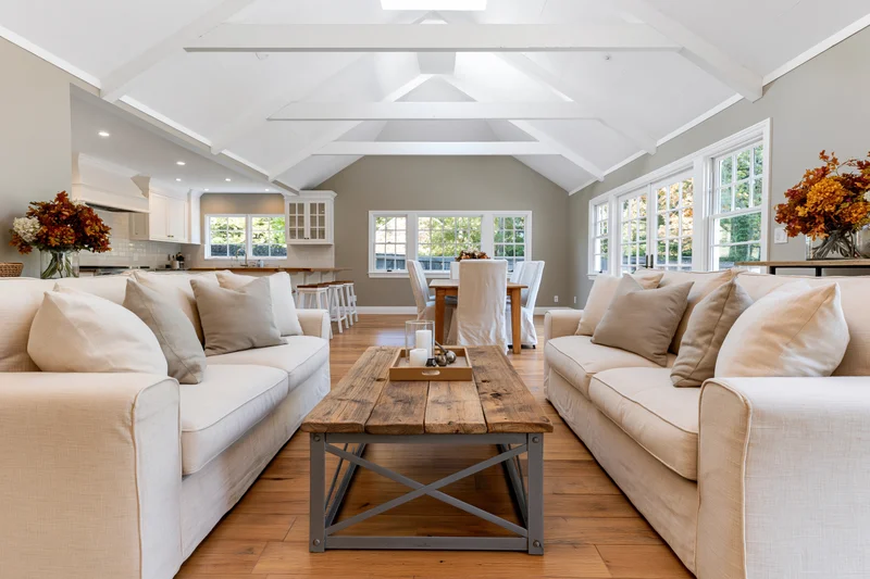 Two cream linen sofas facing each other in an open-plan living room with hardwood floors and vaulted ceiling
