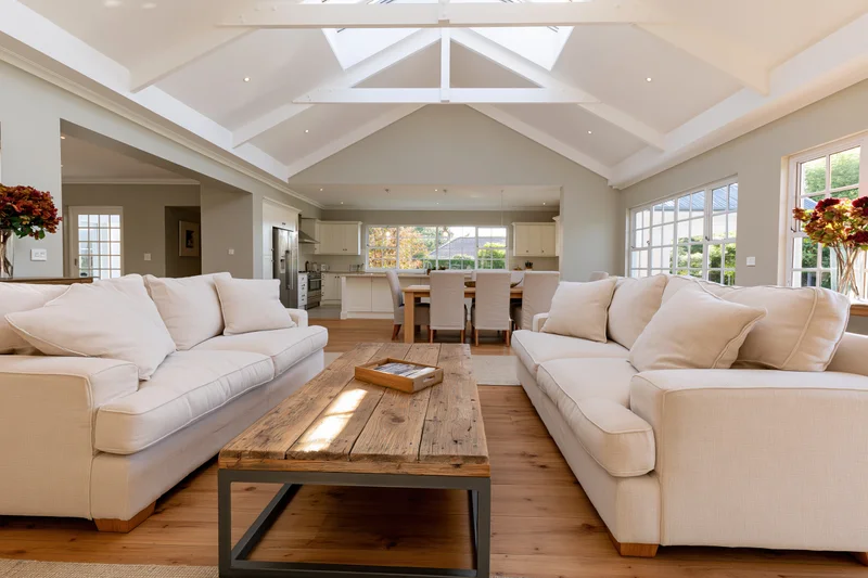 Two cream linen sofas facing each other in an open-plan living room with vaulted ceiling and skylight