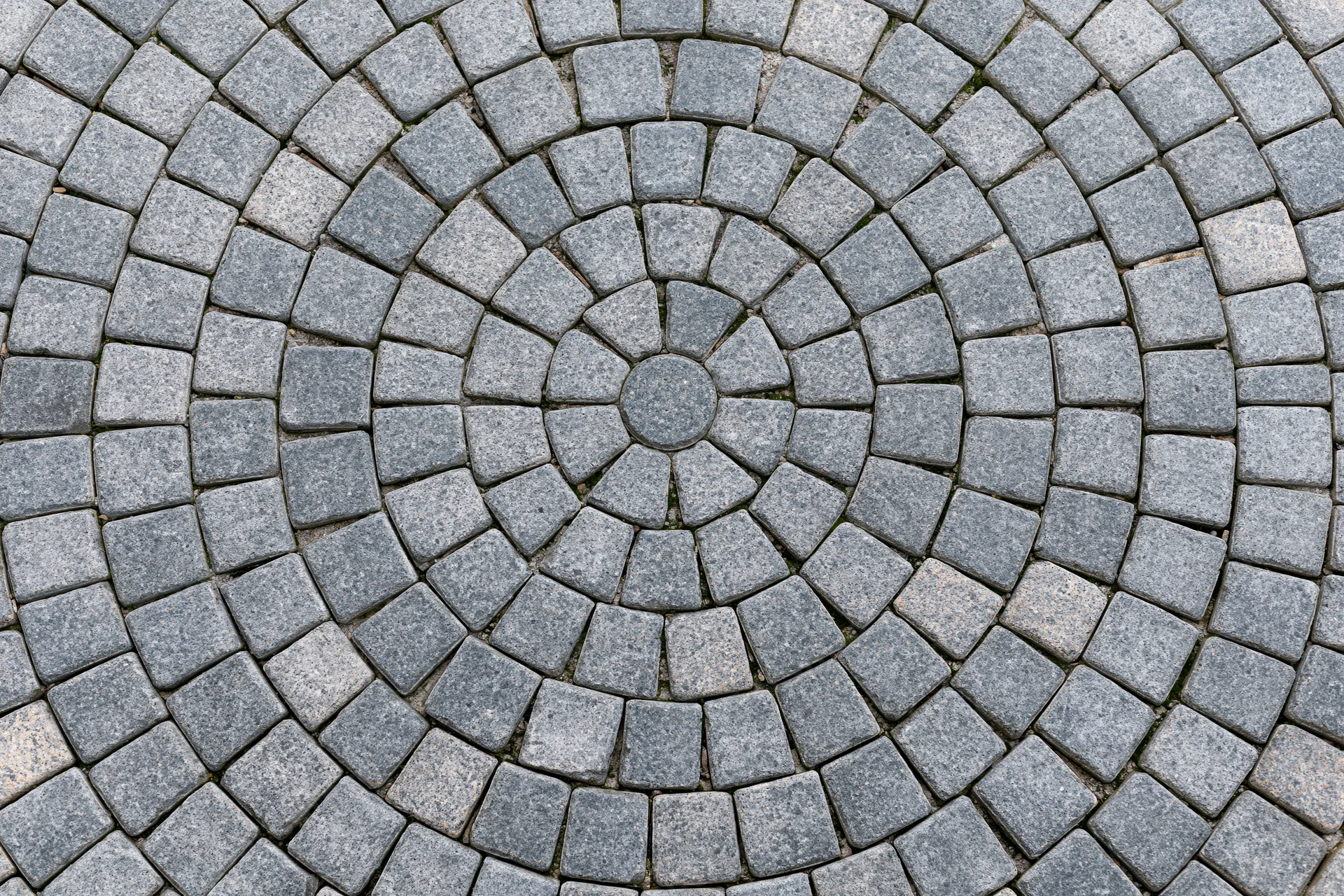 Circular grey cobblestone patio arranged in concentric rings for outdoor flooring