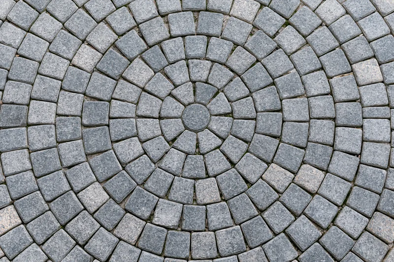 Circular grey cobblestone patio arranged in concentric rings for outdoor flooring