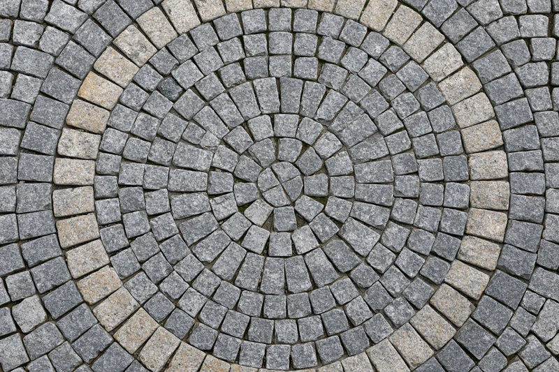 Circular cobblestone patio arranged in concentric rings on outdoor ground surface