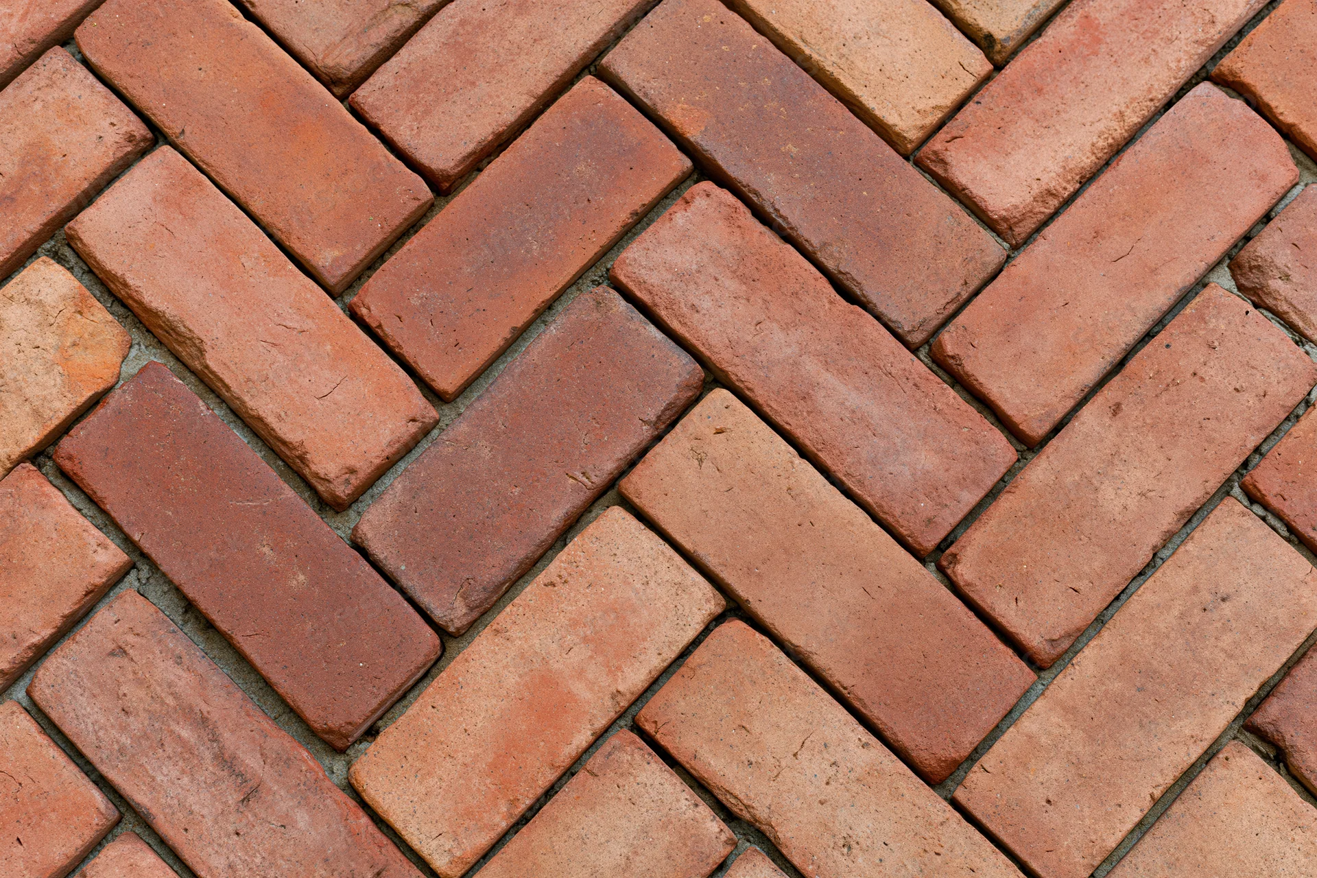 Red clay brick pavers arranged in herringbone pattern for outdoor flooring