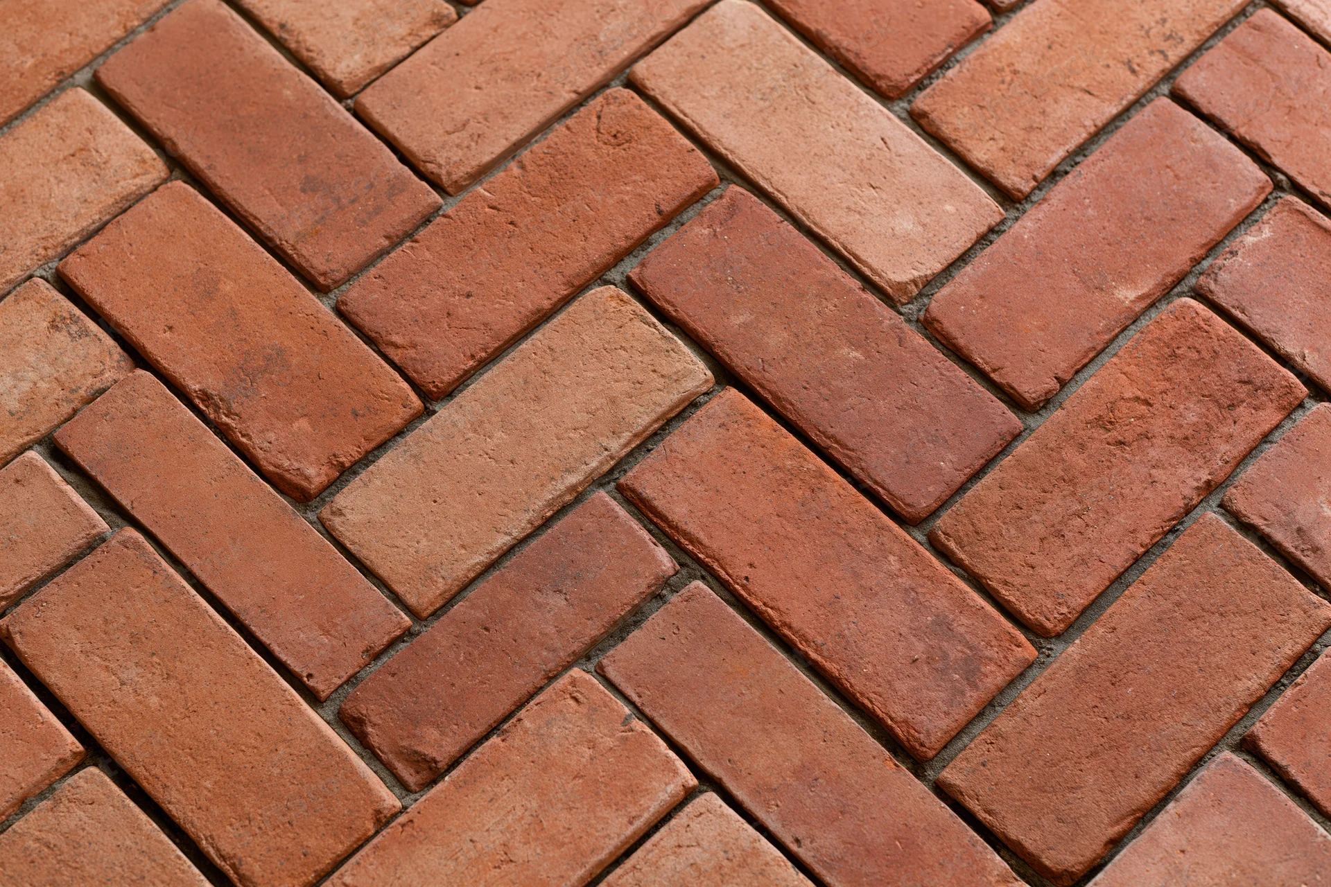 Red clay brick pavers arranged in herringbone pattern for outdoor flooring