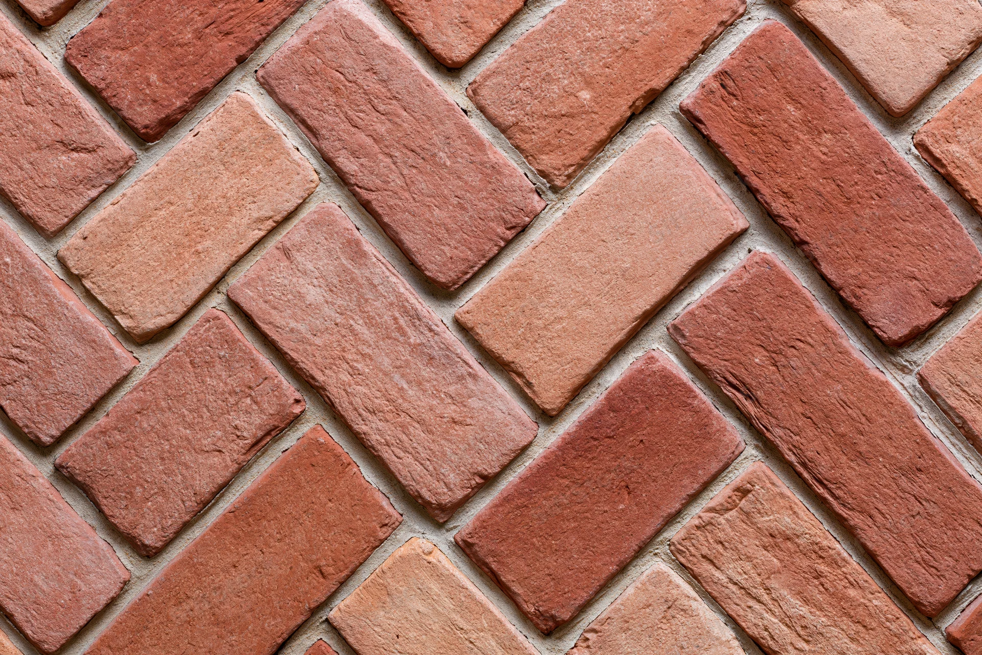 Red clay brick pavers arranged in herringbone pattern for outdoor flooring