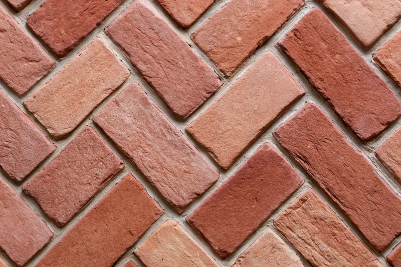 Red clay brick pavers arranged in herringbone pattern for outdoor flooring