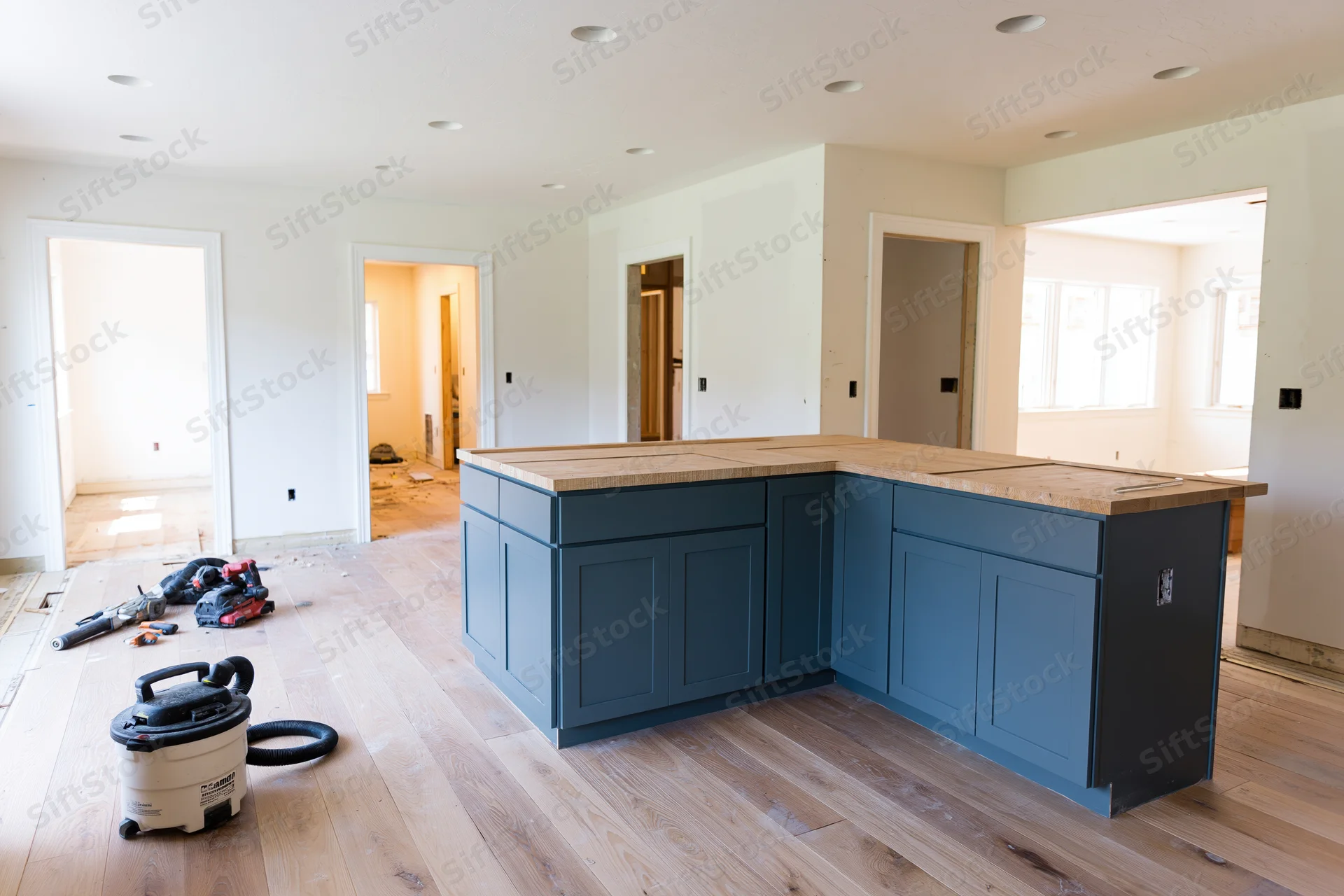 Navy kitchen island with wood countertop installed during home renovation on hardwood floor