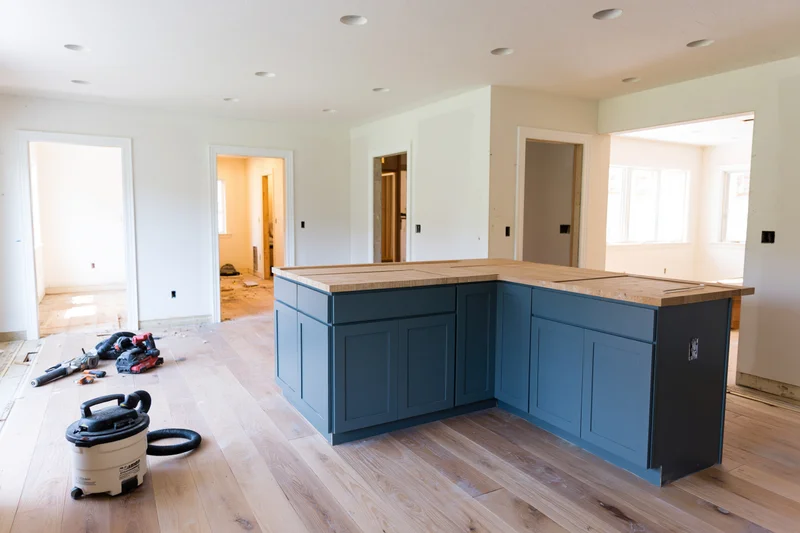 Navy kitchen island with wood countertop installed during home renovation on hardwood floor