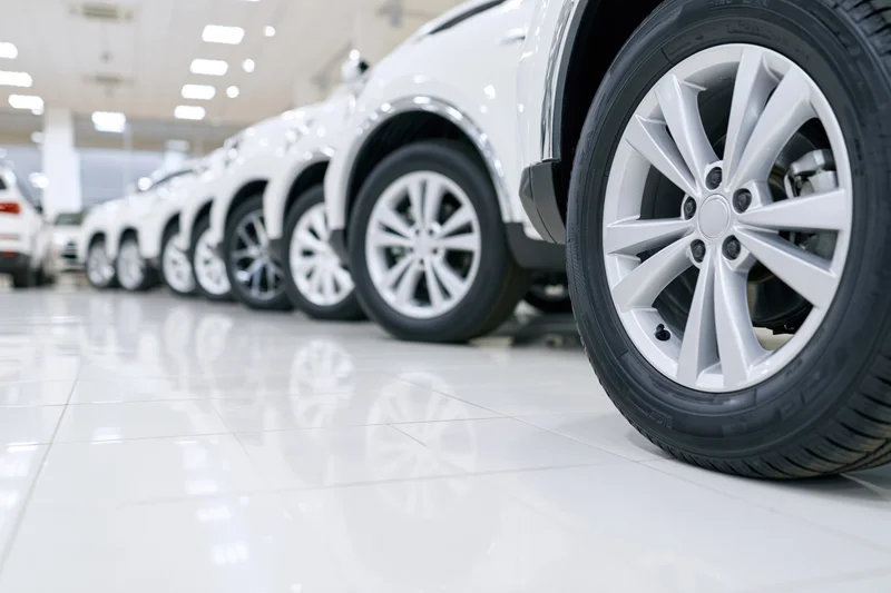 Row of white suvs parked in a car dealership showroom with glossy tiled floor and reflections